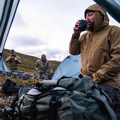man drinking coffee outside a tent